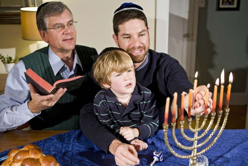 Niño de cuatro años con el abuelo y el padre encendiendo la menorá de Hanukkah. Foto tomada: 21 de diciembre de 2009